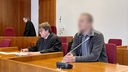 Zu sehen sind zwei Männer in einem Gerichtssaal, einer hat einen verpixelten Kopf.