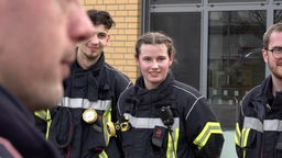 Zwei Männer und eine Frau in Feuerwehruniform.