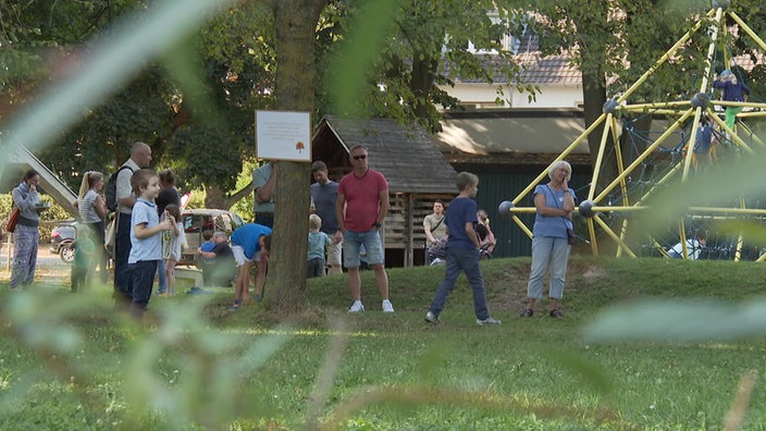 Anwohner im Park in Pulheim vor Bäumen und einem Spielplatz