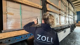 Zoll-Mitarbeiterin begutachtet sichergestellte Zigaretten