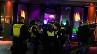 Ordnungsamt und Polizei stehen vor einer Shisha-Bar in Köln und führen eine Razzia durch
