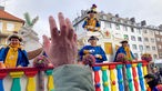 Kostümierte Menschen schmeißen Süßigkeiten von einem Wagen beim Rosenmontagszug in Aachen
