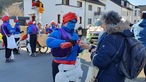 Ein blau-angemalter Mann in Schleiden schenkt einer Frau am Wegesrand etwas zu trinken ein