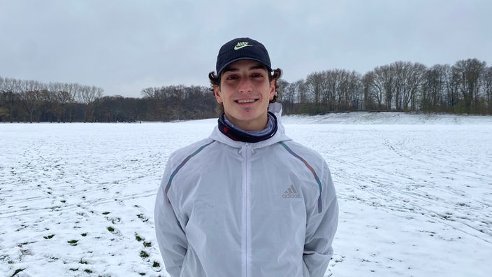 Felix Wittmann steht in Trainingsklamotten auf einem verschneiten Feld