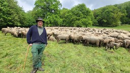 Ein Schäfer posiert vor seiner Schafsherde.