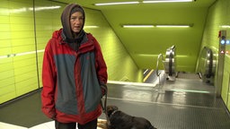 Melanie zeigt, wo sie im Winter die Nächte verbringt: in einer Zwischenebene einer U-Bahn-Haltestelle. Sie schaut dabei in die Kamera.