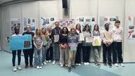 Schüler der Käthe-Kollwitz-Gesamtschule präsentieren ihre Arbeiten zum Anne Frank Gedenktag vor einer Posterwand