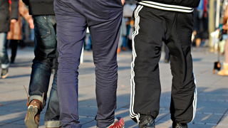 Drei Menschen laufen nebeneinander. Einer von ihnen trägt eine Jogginghose.
