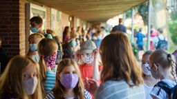 Schüler mit Masken stehen auf einem Schulhof