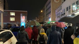 Das Bild zeigt eine Menschenmenge mit Regenschirmen