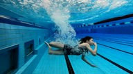 Schwimmerin unter Wasser in einem Schwimmbadbecken