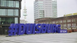 Auf dem Foto ist ein Platz, auf dem in riesigen Skulpturbuchstaben "#DUISBURG IST ECHT" steht.
