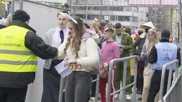 Eine Sicherheitskraft kontrolliert Feiernde in Köln.