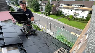 Ein Dachdecker beim decken eines Daches mit den Solardachpfannen.