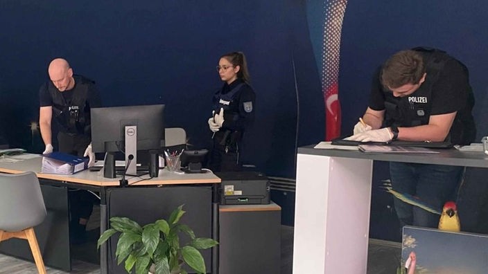 Polizisten durchsuchen ein Reisebüro