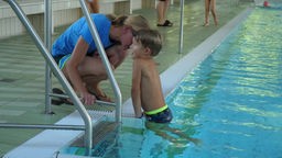Ein Junge, der ungern schwimmen möchte im Hallenbad, aufgrund der niedrigen Temperatur.
