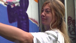 Blonde Frau steht vor Graffiti-Wand