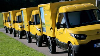 Vier Streetscooter der deutschen Post hintereinander auf einem Feldweg