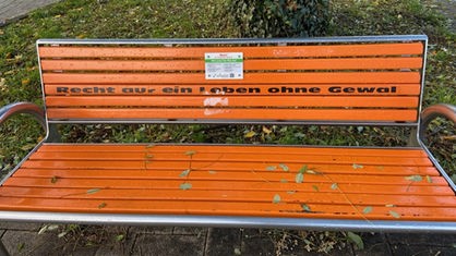 Eine orangene Bank mit dem Schriftzug "Recht auf ein Leben ohne Gewalt".