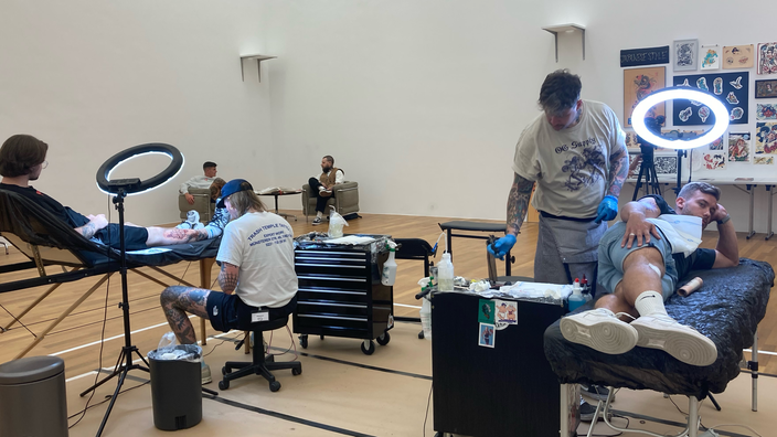 Zwei Männer lassen sich beim Tattoo-Flash im Bonner Kunstmuseum ein Tattoo stechen
