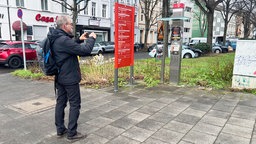 Udo Schneider fotografiert eine Telefonzelle in der Bonner Innenstadt.