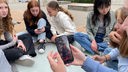 Eine Gruppe Schülerinnnen sitzt auf dem Schulhof und schaut Handyvideos