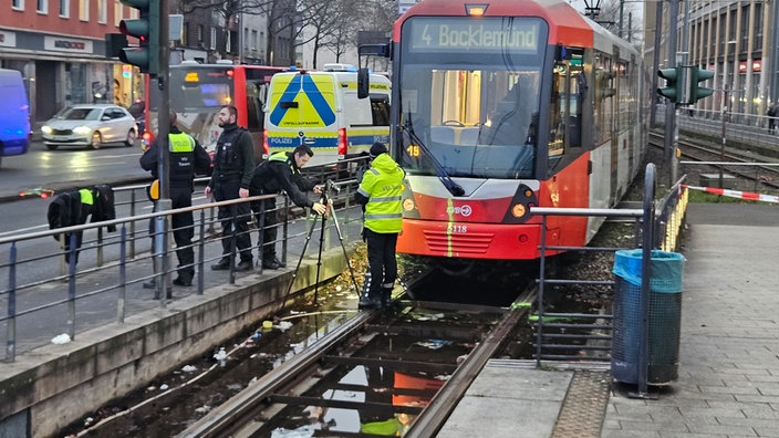 Ein Unfallteam der Polizei untersucht die Unfallstelle am Wiener Platz in den Bahngleisen, im Hintergrund steht eine Bahn der KVB.