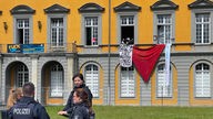 Eine rote Fahne und Schriftbänder hängen aus dem Unigebäude in Bonn heraus