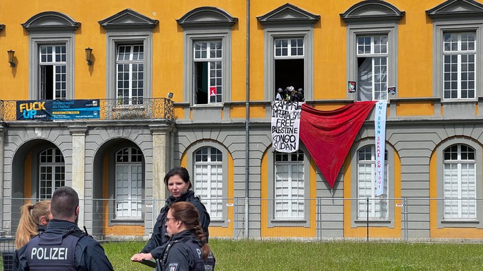 Eine rote Fahne und Schriftbänder hängen aus dem Unigebäude in Bonn heraus