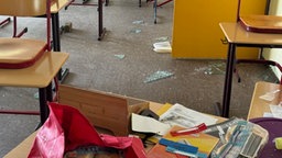 Klassenzimmer mit Glasscherben und verstreuten Unterlagen