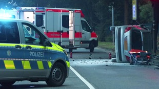 Polizei und Rettungswagen, das Unfallfahrzeug liegt mit zersörtet Heckscheibe auf der Beifahrerseite