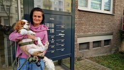 Anwohnerin von gegenüber Ebru Güvenc, vor der Haustür zu sehen mit ihrem Hund auf dem Arm.
