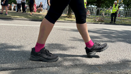 Die Beine einer wandernden Person mit schwarzen Schuhen und pinken Socken