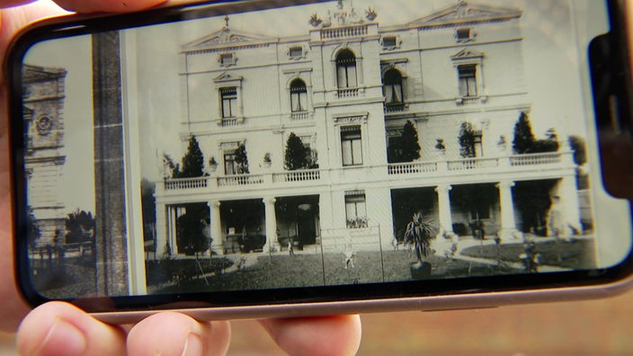 Abfotografiertes Handydisplay mit einem Bild von der Villa Buth in glänzenden Tagen