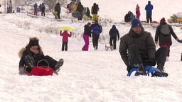 Viele Menschen fahren Schlitten oder amüsieren sich im Schnee.