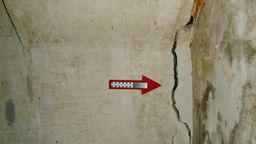 Ein Pfeil zeigt auf einen Riss in einer Wand.