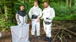 Drei Männer im Wald in weißen Anzügen mit Forschungsequipment
