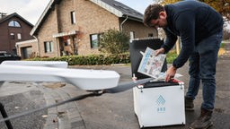 Johannes Heinen, Geschäftsführer des Heinen Verlages, steckt Zeitungen in eine Transportbox für eine Drohne. 
