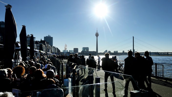 Menschen genießen an der Düsseldorfer Rheinpromenade in Düsseldorf das Wetter. Auch das Wochenende bleibt frühlingshaft. 