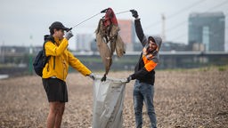 Mustafa und Sayed (l) helfen freiwillig im Rahmen der Müllsammelaktion RhineCleanUp am Oberkasseler Rheinufer