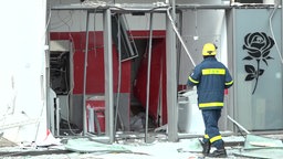 Eine Einsatzkraft des THW läuft zum gesprengten Geldautomaten der Sparkasse in einem Supermarkt