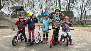 Fünf Kinder stehen nebeneinander mit ihren Laufrädern und den neuen Helmen.
