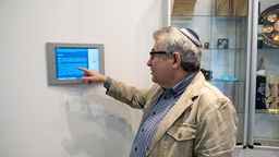 Ein Mann zeigt in einem Museum auf ein Tablet-Computer.