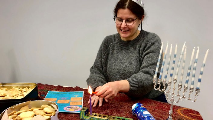 Jüdische Frau vor Chanukka-Leuchtern zündet Kerze an