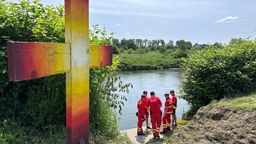Ehrenamtliche von der DLRG stehen an der Ruhr und sichern das Gewässer für die Taufe ab.