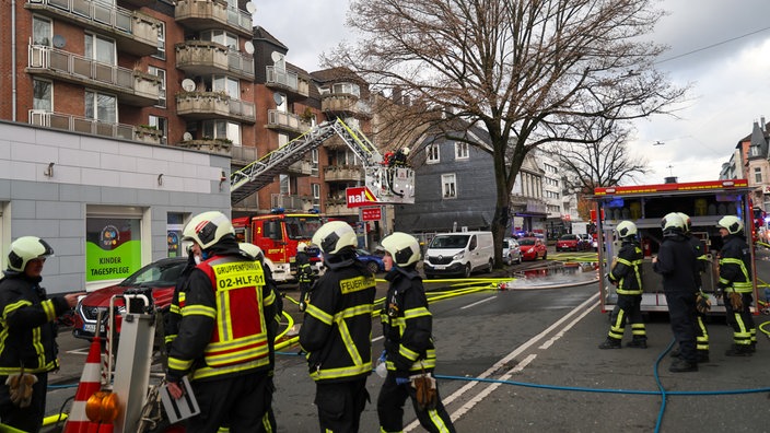 Das Bild zeigt Feuerwehrleute im Einsatz bei einem Wohnhausbrand.