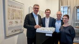 Auf dem Bild sind vier Menschen zu sehen, ganz außen links steht der Dortmunder Oberbürgermeister Thomas Westphal. Im Vordergrund steht die Modellierung für das neue Karlsquartier.