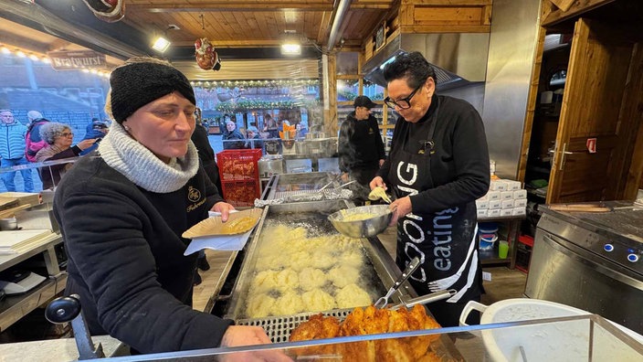 Frauen an Friteusen in Weihnachtsmarktstand