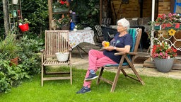 Ingeborg Krause sitzt auf einem Liegestuhl vor ihrem Gartenhaus