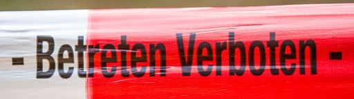 Rot-weiß gestreiftes Flatterband, auf dem "Betreten verboten" zu lesen ist